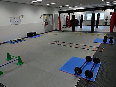 Zaal ingericht voor Total Body Workout met bokszakken, loopladder, plyobox en halters